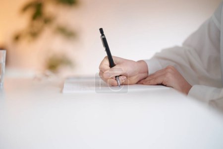 Photo for Young woman writing in notebook in the room - Royalty Free Image