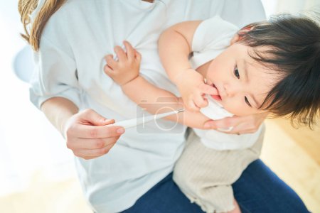 Photo for A little boy having his mother measure his temperature - Royalty Free Image