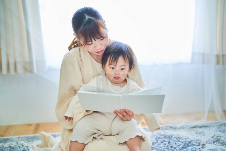 Téléchargez les photos : Jeune mère et petit enfant lisant un livre d'images - en image libre de droit