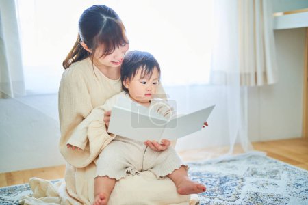 Junge Mutter und kleines Kind lesen ein Bilderbuch