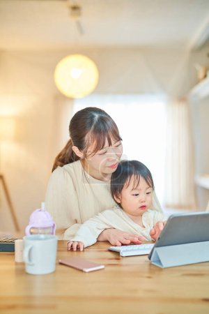Téléchargez les photos : Jeune mère tenant un bébé et utilisant un ordinateur - en image libre de droit