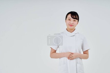 Foto de Young woman wearing a white coat indoors and white background - Imagen libre de derechos