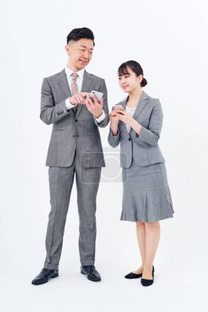 Téléchargez les photos : Man and woman in suits with smartphones and white background - en image libre de droit