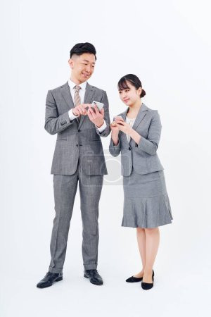 Foto de Man and woman in suits with smartphones and white background - Imagen libre de derechos