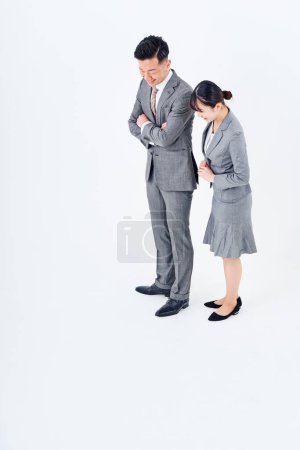 Téléchargez les photos : Homme et femme en costume regardant vers le bas de l'écran et fond blanc - en image libre de droit
