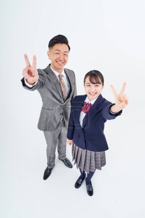 Foto de Un hombre y una chica de secundaria en un traje haciendo un signo de paz y fondo blanco - Imagen libre de derechos