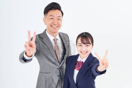 Téléchargez les photos : A man and a high school girl in a suit doing a peace sign and white background - en image libre de droit