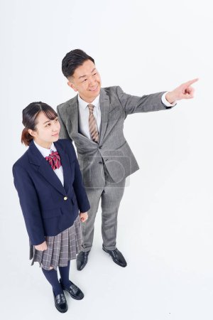Téléchargez les photos : A man and a high school girl in a suit pointing up and white background - en image libre de droit