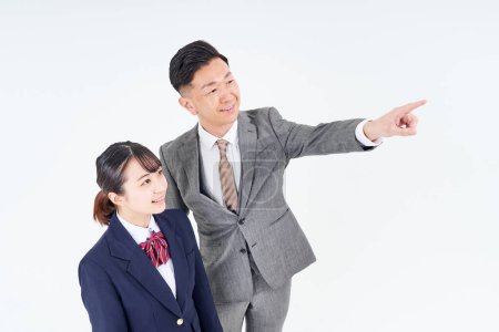 Téléchargez les photos : A man and a high school girl in a suit pointing up and white background - en image libre de droit