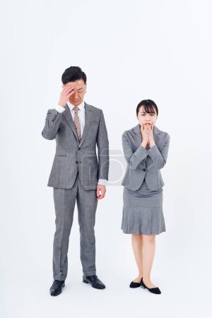 Foto de Hombre y mujer en trajes con expresiones estresadas y fondo blanco - Imagen libre de derechos