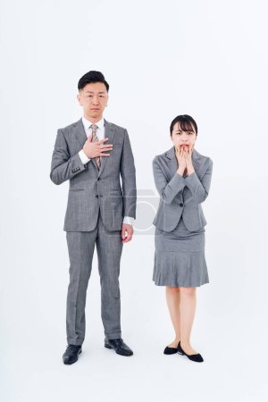Foto de Man and woman in suits with stressed expressions and white background - Imagen libre de derechos