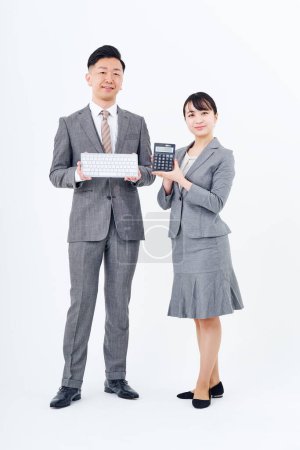 Téléchargez les photos : Homme et femme en costumes avec claviers et calculatrices et fond blanc - en image libre de droit