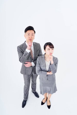 Téléchargez les photos : A man and woman in a suit who poses a question and white background - en image libre de droit