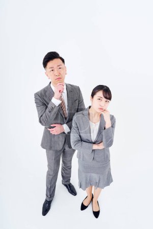 Téléchargez les photos : A man and woman in a suit who poses a question and white background - en image libre de droit