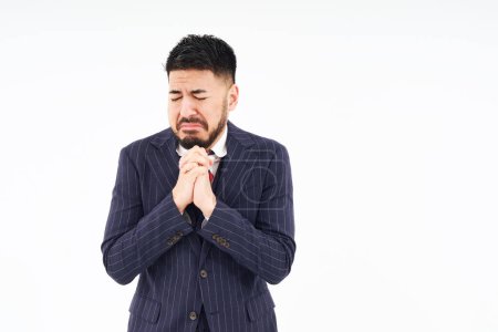 Photo for A man in a suit doing a praying pose and white background - Royalty Free Image