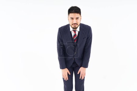 Foto de A man in a suit who poses to apologize and white background - Imagen libre de derechos