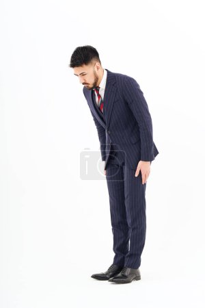 Foto de A man in a suit who poses to apologize and white background - Imagen libre de derechos