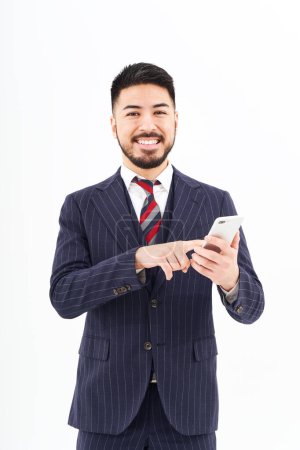 Foto de A man in a suit operating a smartphone and white background - Imagen libre de derechos