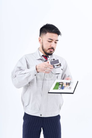 Téléchargez les photos : Un homme en vêtements de travail avec un modèle de maison et fond blanc - en image libre de droit