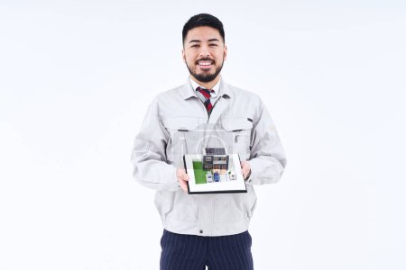 Foto de A man in work clothes with a house model and white background - Imagen libre de derechos