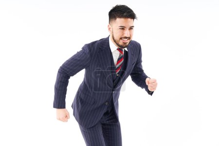 Photo for A man in a suit doing a running pose and white background - Royalty Free Image
