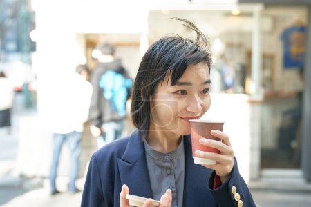 Téléchargez les photos : Jeune femme prenant un verre au coin de la rue - en image libre de droit