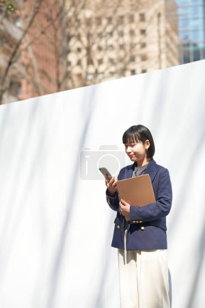 Téléchargez les photos : Une femme qui regarde son smartphone à l'extérieur - en image libre de droit