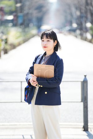 Téléchargez les photos : Une jeune femme dans un style décontracté de bureau debout sur un coin de rue - en image libre de droit