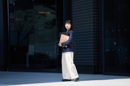 Foto de Una joven en una oficina de estilo casual de pie en una esquina de la calle - Imagen libre de derechos