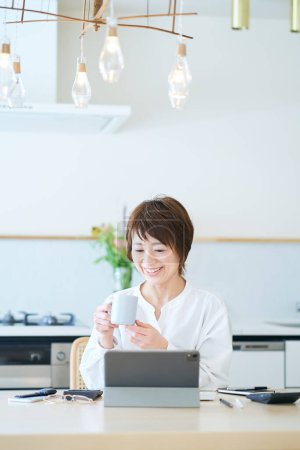 Photo for Woman communicating online in dining kitchen of the room - Royalty Free Image