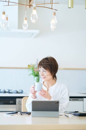 Foto de Una mujer tomando un descanso con una taza mientras trabaja desde casa - Imagen libre de derechos