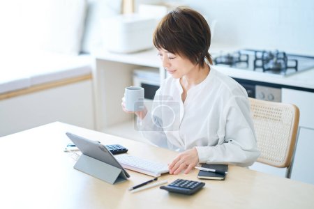 Téléchargez les photos : Une femme qui fait une pause avec une tasse tout en travaillant à la maison - en image libre de droit