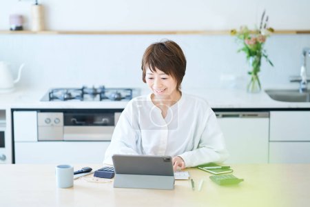 Woman communicating online in dining kitchen of the room