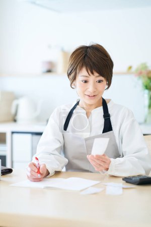 Photo for A woman in an apron checking receipts in the room - Royalty Free Image