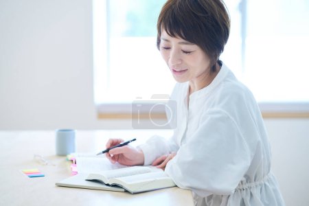 Foto de Una mujer treintañera estudiando por texto en la habitación - Imagen libre de derechos