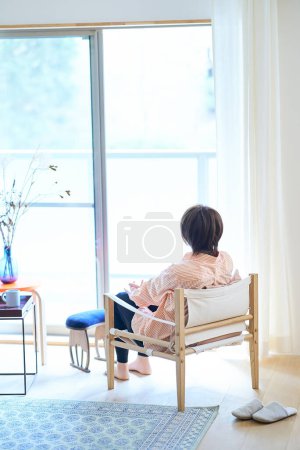 Foto de Mujer relajándose junto a la ventana de su habitación - Imagen libre de derechos