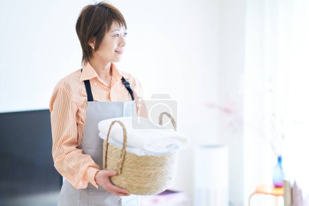 Photo for A woman in an apron with laundry in the room - Royalty Free Image