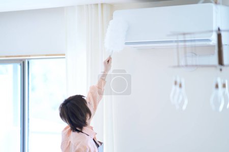 Téléchargez les photos : Asiatique femme nettoyage l 'poussière dans l' chambre - en image libre de droit