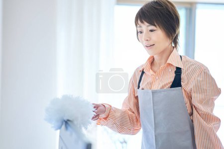 Téléchargez les photos : Asiatique femme nettoyage l 'poussière dans l' chambre - en image libre de droit