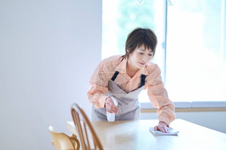 Foto de Mujer limpiando la mesa del comedor en la habitación - Imagen libre de derechos