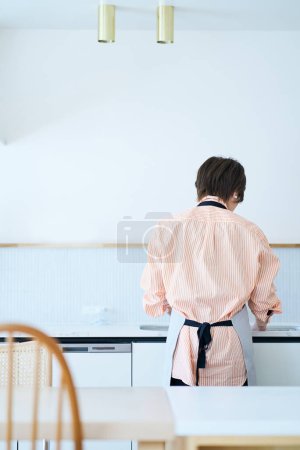 Photo for Rear view of a woman washing dishes in the kitchen - Royalty Free Image