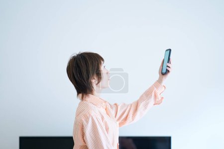 Foto de Una mujer sosteniendo un smartphone en el interior - Imagen libre de derechos