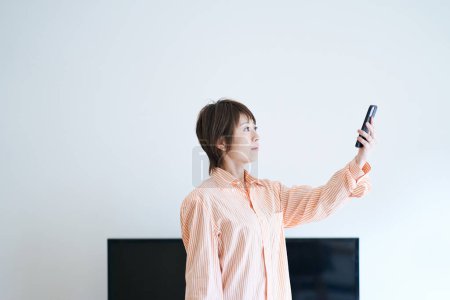 Téléchargez les photos : Une femme tenant un smartphone à l'intérieur - en image libre de droit