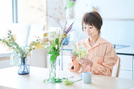 Foto de Mujer arreglando flores con florero en la habitación - Imagen libre de derechos