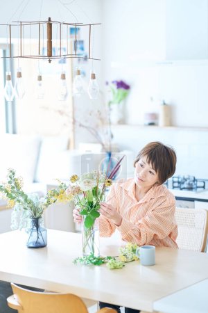 Photo for Woman arranging flowers with flower vase in the room - Royalty Free Image