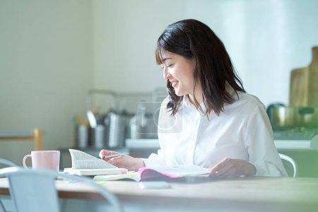 Foto de Mujer adulta estudiando con texto en casa - Imagen libre de derechos