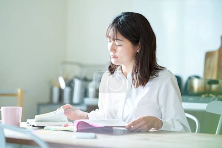 Foto de Mujer adulta estudiando con texto en casa - Imagen libre de derechos