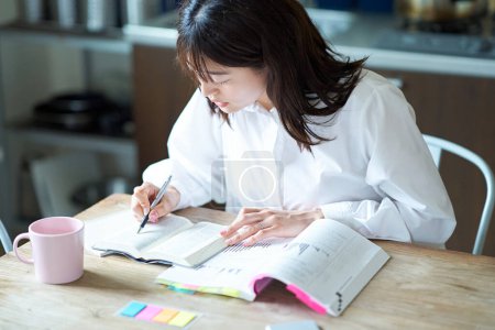 Photo for Adult woman studying with text at home - Royalty Free Image