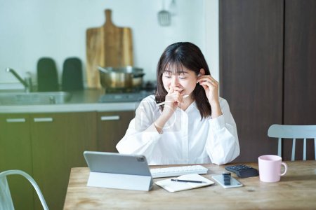 Téléchargez les photos : Asiatique femme d'affaires communiquant en ligne dans son salon - en image libre de droit