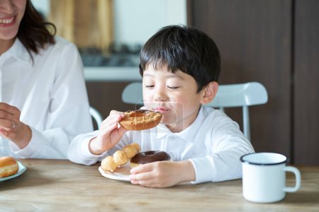 mother and son eating donut at home